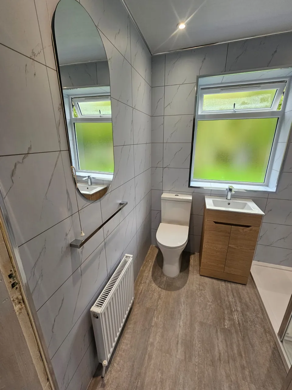 Compact shower room with oak vanity and marble-effect walls